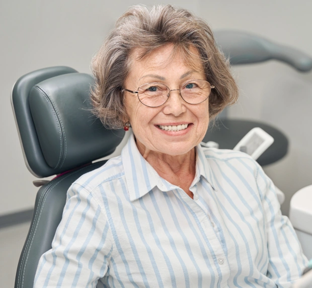 Senior patient smiling after dental implant treatment at Saginaw Family Smiles